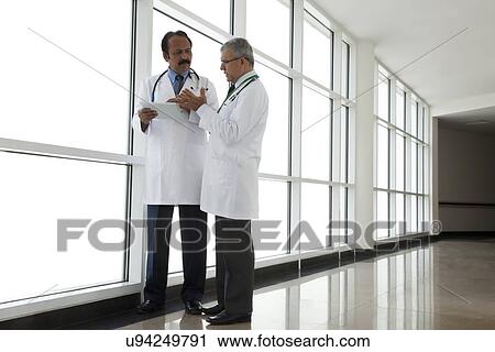 Two doctors talking in corridor of hospital View Large Photo Image Stock Image - Two doctors talking in corridor of hospital. Fotosearch
