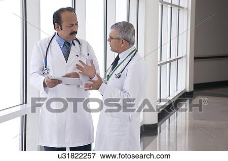 Stock Photo - Two doctors talking in corridor of hospital. Fotosearch