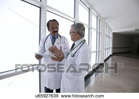 Two doctors talking in corridor of hospital View Large Photo Image Stock Photo - Two doctors talking in corridor of hospital. Fotosearch