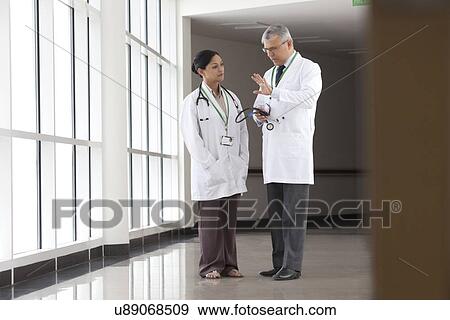 Two doctors talking in corridor of hospital View Large Photo Image Stock Photo - Two doctors talking in corridor of hospital. Fotosearch