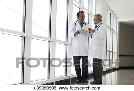 Stock Photograph - Two doctors talking in corridor of hospital. Fotosearch