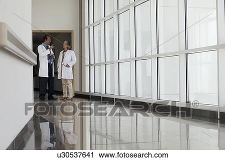Stock Image - Two doctors talking in hospital corridor. Fotosearch