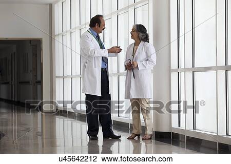 Stock Image - Two doctors talking in hospital corridor. Fotosearch