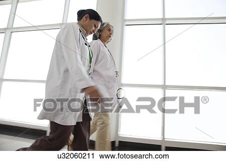 Two doctors walking in hospital corridor View Large Photo Image Stock Image - Two doctors walking in hospital corridor. Fotosearch