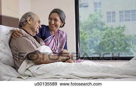Stock Photo - Wife sitting with her husband in the hospital . Fotosearch