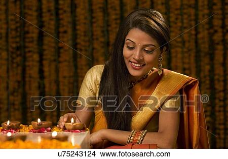 Picture - Woman arranging diyas . Fotosearch