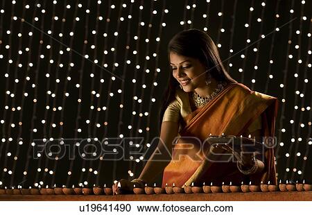 Stock Image - Woman arranging diyas . Fotosearch