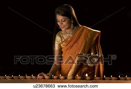 Stock Image - Woman arranging diyas . Fotosearch