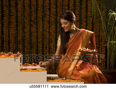 Stock Image - Woman arranging diyas . Fotosearch