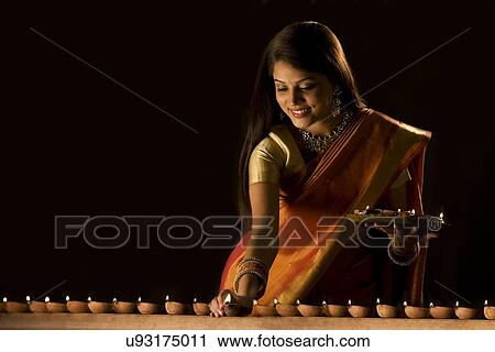 Stock Image - Woman arranging diyas . Fotosearch