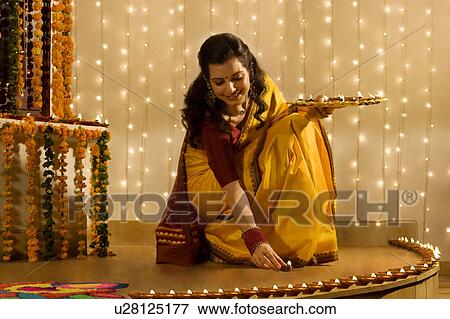 Stock Photo - Woman arranging diyas . Fotosearch