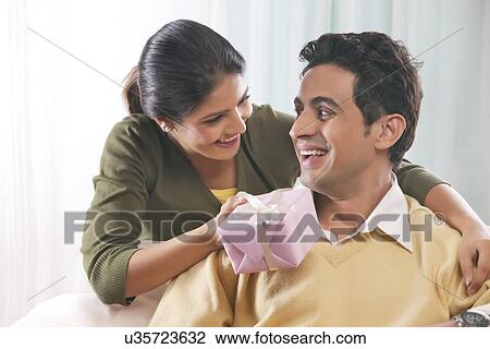 Woman giving a man a gift on Valentines Day View Large Photo Image Stock Image - Woman giving a man a gift on Valentines Day. Fotosearch