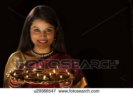 Woman holding a tray with diyas View Large Photo Image Stock Photo - Woman holding a tray with diyas . Fotosearch