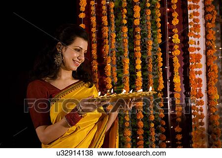 Woman holding a tray with diyas View Large Photo Image Stock Photo - Woman holding a tray with diyas . Fotosearch