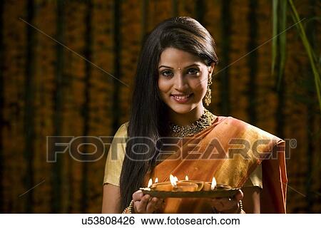 Stock Photograph - Woman holding a tray with diyas . Fotosearch