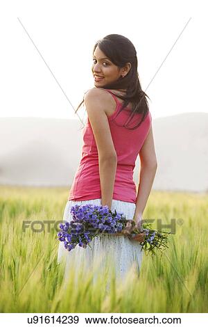 Woman holding flowers in a field View Large Photo Image Stock Photo - Woman holding flowers in a field . Fotosearch