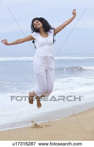 Stock Photo - Woman jumping in the air at a beach . Fotosearch