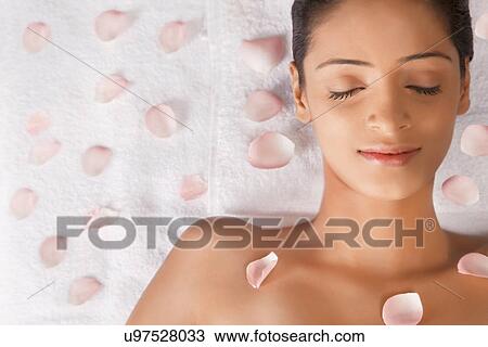 Stock Image - Woman lying on massage table with petals . Fotosearch