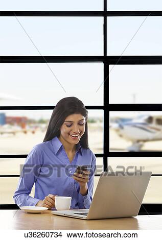 Woman reading an sms on a mobile phone View Large Photo Image Picture - Woman reading an sms on a mobile phone . Fotosearch