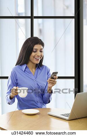 Stock Image - Woman reading an sms on a mobile phone . Fotosearch