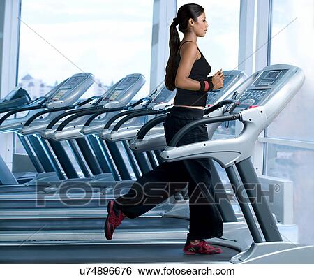 Stock Photograph - Woman running on a treadmill in a gym . Fotosearch