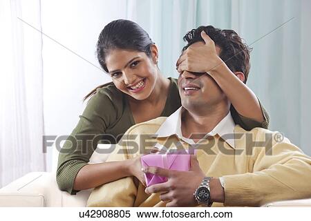 Woman surprising a man with a gift on Valentines Day View Large Photo Image Stock Photography - Woman surprising a man with a gift on Valentines Day. Fotosearch