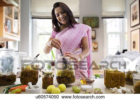 Stock Image - Woman taking pickle out of a jar . Fotosearch