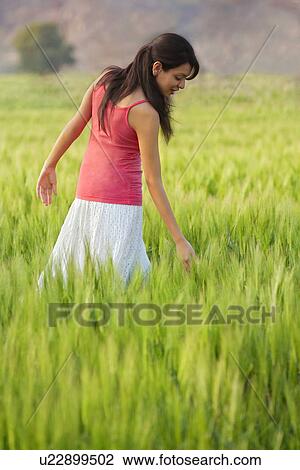 Stock Image - Woman walking through a field . Fotosearch