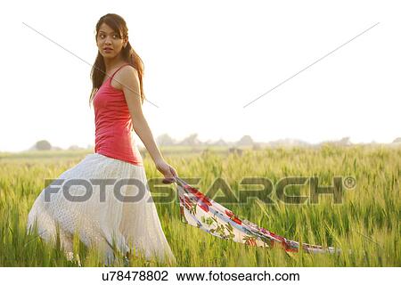 Stock Image - Woman walking through a field . Fotosearch
