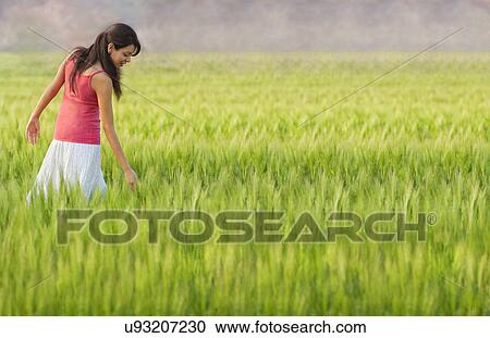 Stock Image - Woman walking through a field . Fotosearch