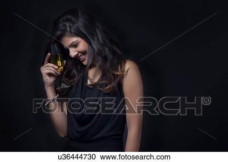 Stock Image - Woman with a glass of wine enjoying herself. Fotosearch