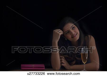 Stock Photograph - Woman with a glass of wine reminiscing. Fotosearch