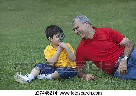 Young boy looking at grandfather through magnifying glass View Large Photo Image Picture - Young boy looking at grandfather through magnifying glass. Fotosearch