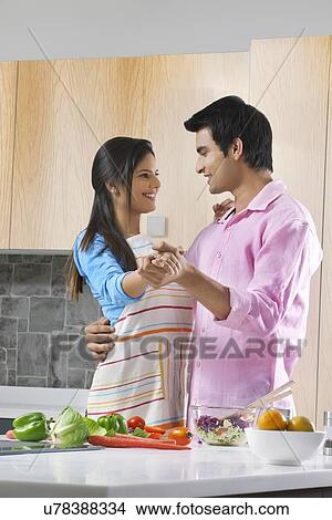 Picture - Young couple dancing while preparing food in kitchen. Fotosearch