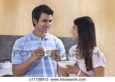 Stock Image - Young couple having coffee and pasta in kitchen. Fotosearch
