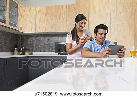 Young couple using digital tablet in kitchen View Large Photo Image Stock Photo - Young couple using digital tablet in kitchen. Fotosearch