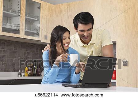 Young couple using laptop in kitchen View Large Photo Image Picture - Young couple using laptop in kitchen. Fotosearch