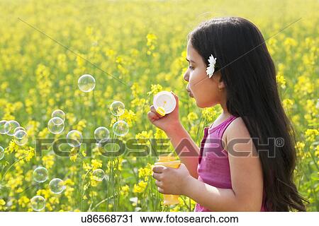 Young girl blowing bubbles in a field View Large Photo Image Stock Image - Young girl blowing bubbles in a field . Fotosearch