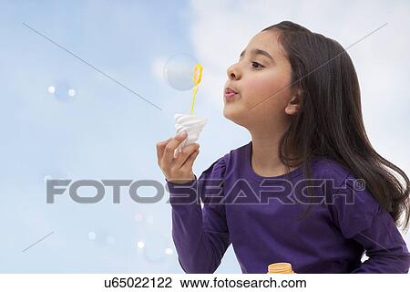 Stock Image - Young girl blowing bubbles . Fotosearch