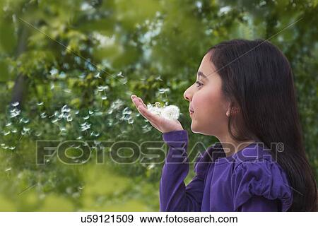 Stock Photo - Young girl blowing on a dandelion . Fotosearch