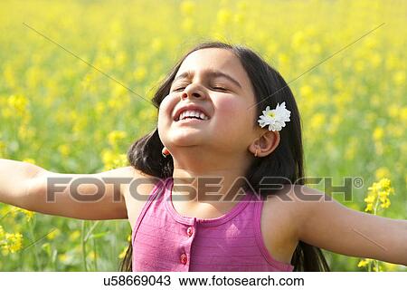 Stock Image - Young girl enjoying herself in a field . Fotosearch