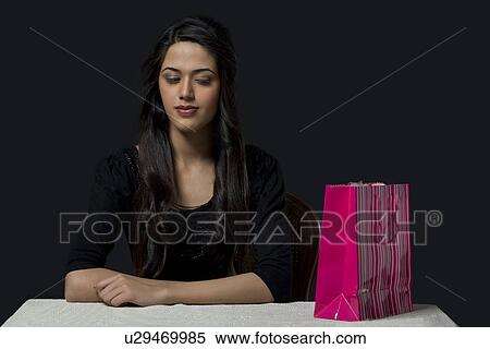Stock Photography - Young girl looking at a shopping bag . Fotosearch