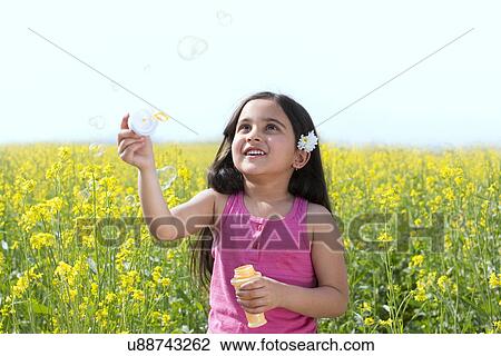 Young girl making bubbles in a field View Large Photo Image Stock Image - Young girl making bubbles in a field . Fotosearch
