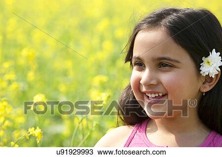 Stock Image - Young girl with a flower in her hair . Fotosearch