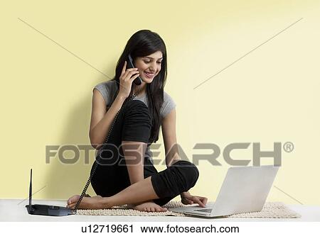 Young girl with a laptop talking on a phone View Large Photo Image Stock Image - Young girl with a laptop talking on a phone . Fotosearch