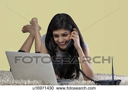 Young girl with a laptop talking on a phone View Large Photo Image Stock Image - Young girl with a laptop talking on a phone . Fotosearch
