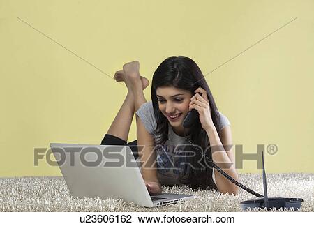 Young girl with a laptop talking on a phone View Large Photo Image Stock Image - Young girl with a laptop talking on a phone . Fotosearch