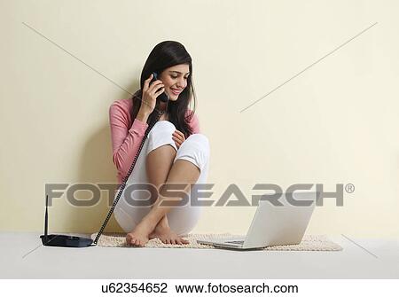 Young girl with a laptop talking on a phone View Large Photo Image Stock Image - Young girl with a laptop talking on a phone . Fotosearch
