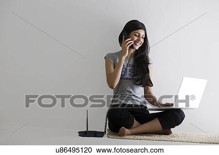 Young girl with a laptop talking on a phone View Large Photo Image Stock Image - Young girl with a laptop talking on a phone . Fotosearch