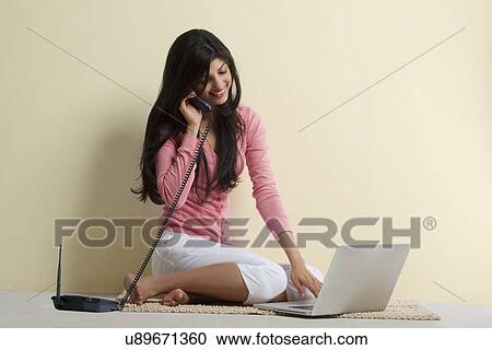 Young girl with a laptop talking on a phone View Large Photo Image Stock Image - Young girl with a laptop talking on a phone . Fotosearch